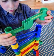 Pictureof a boy building a tower with pieces of assorted primary colors.